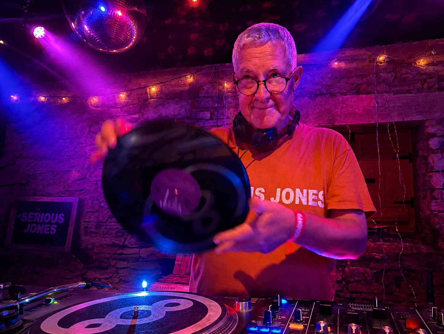 DJ Serious Jones spinning a record under a mirrorball, mid-set at a Making Hay late-night session